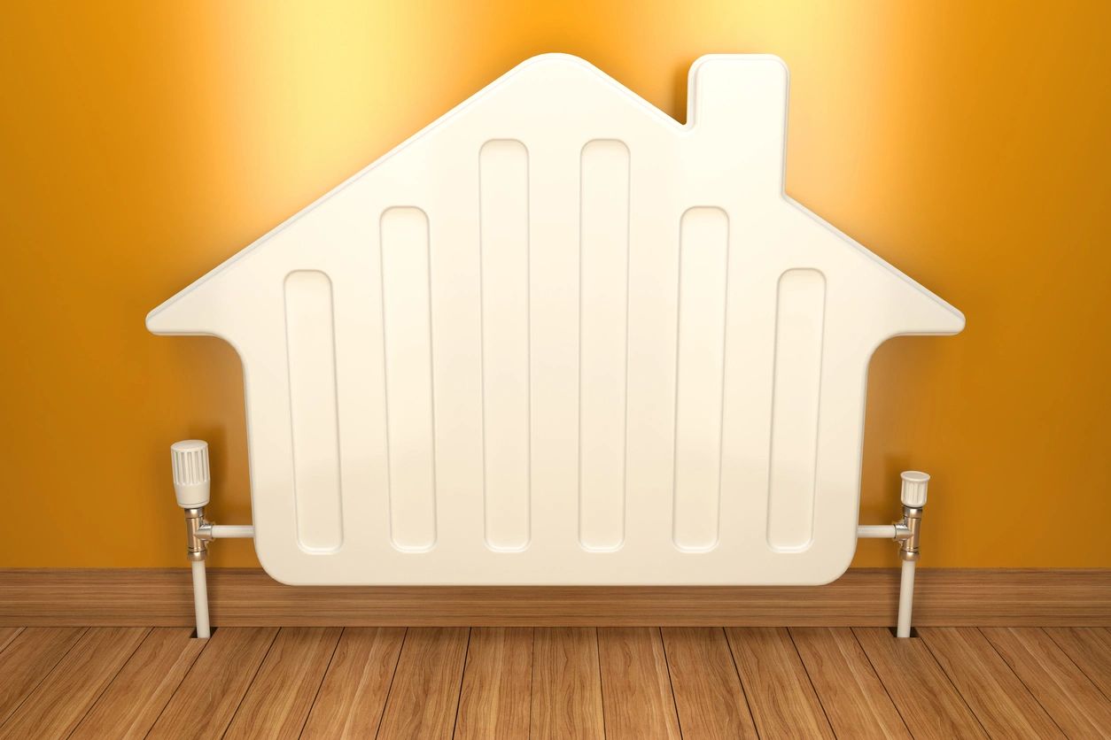 Radiator shaped like a home against an orange wall